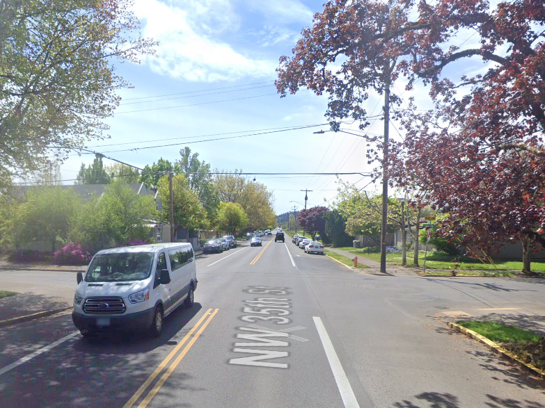 A three-lane street on a sunny day, with a white van driving on the left. 