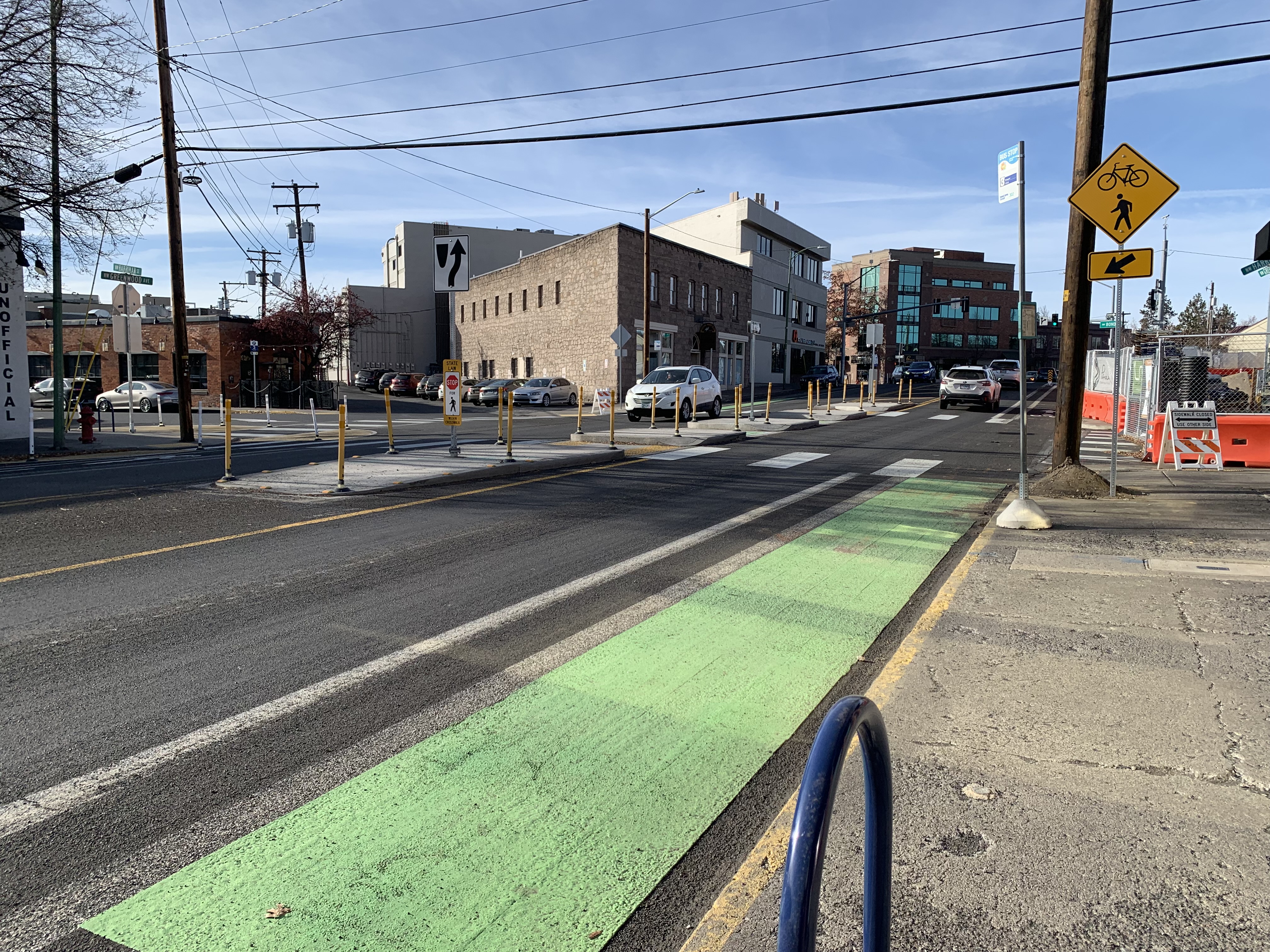 A concrete median island at an intersection on a neighborhood street, narrowing the crossing distance for pedestrians.