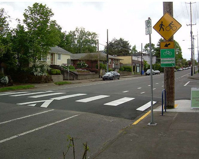 A crosswalk elevated to sidewalk height across a street, with a pedestrian crossing sign visible.