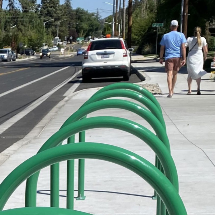 Pedestrians walking on a wide paved path separated from the roadway.